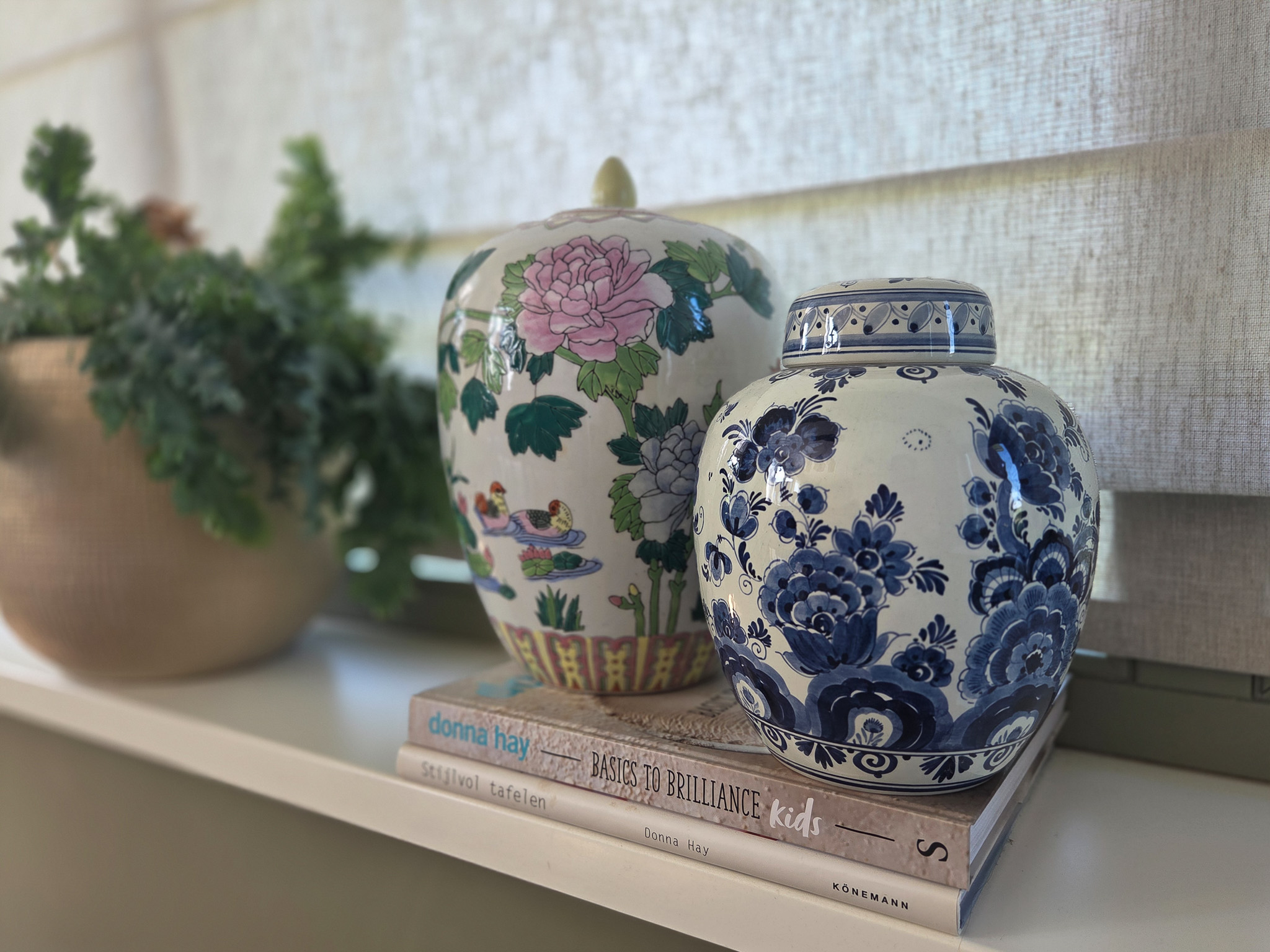 Delftsblauwe pot en kleurrijke vaas op vensterbank met boeken — interieurfotografie detail